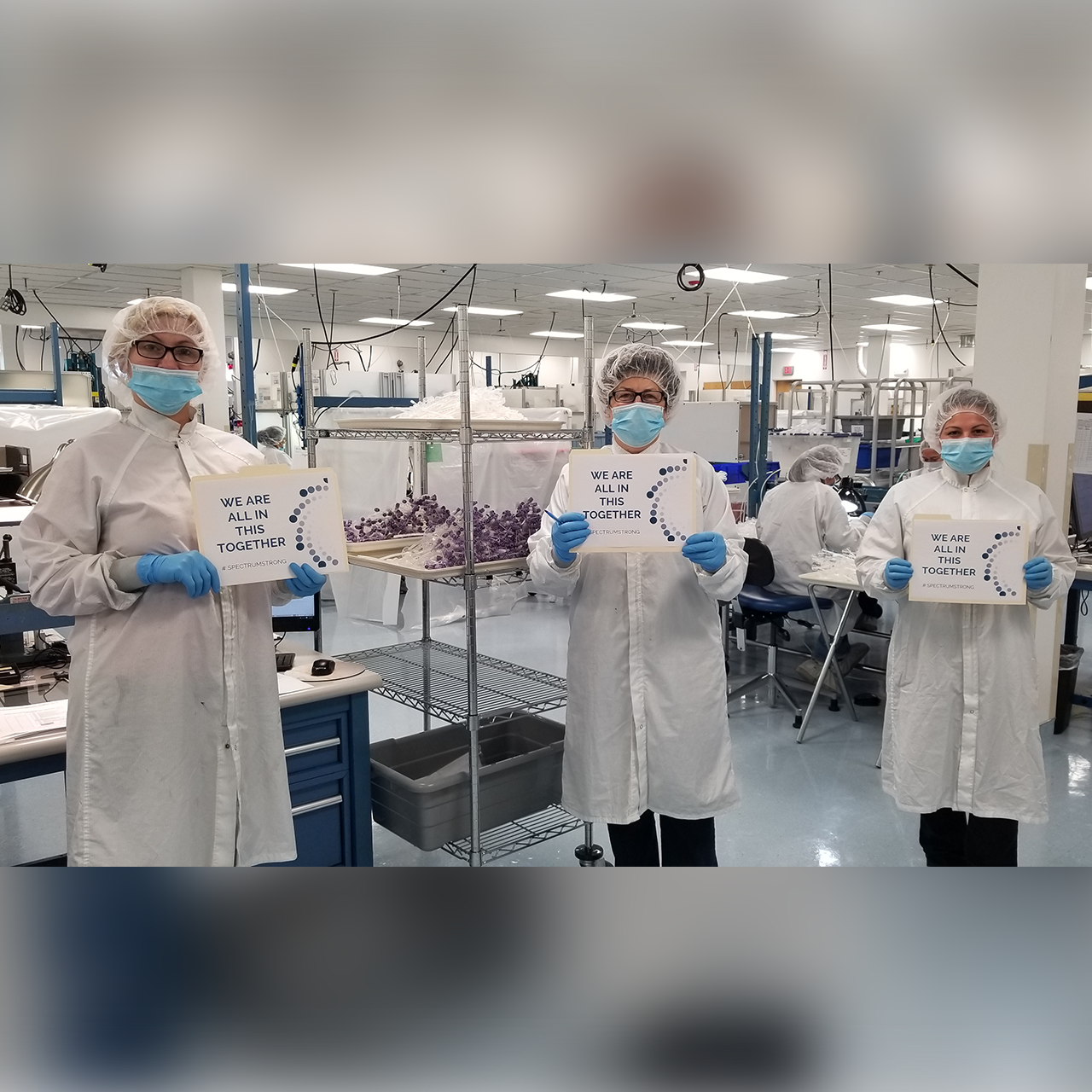 Spectrum Plastics' extrusion specialists holding "We Are All in This Together" signs